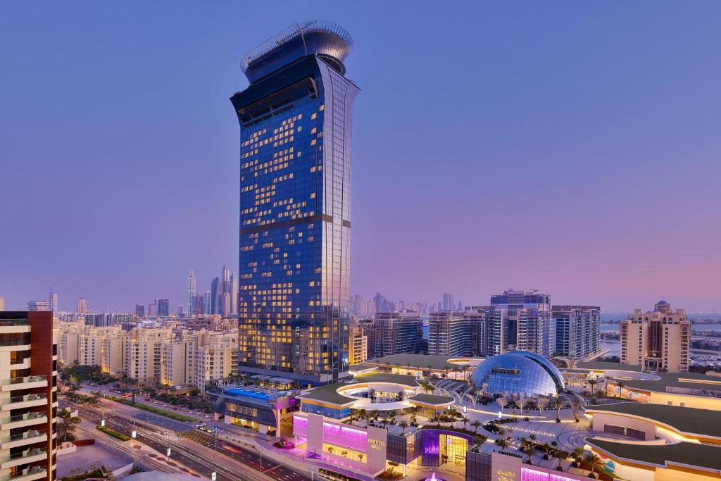 Tall glass hotel tower rising above a city skyline at twilight